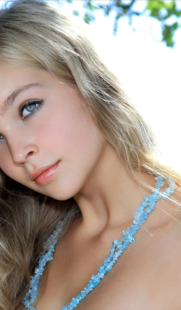 Красивая голубоглазая девушка с бусами на шее