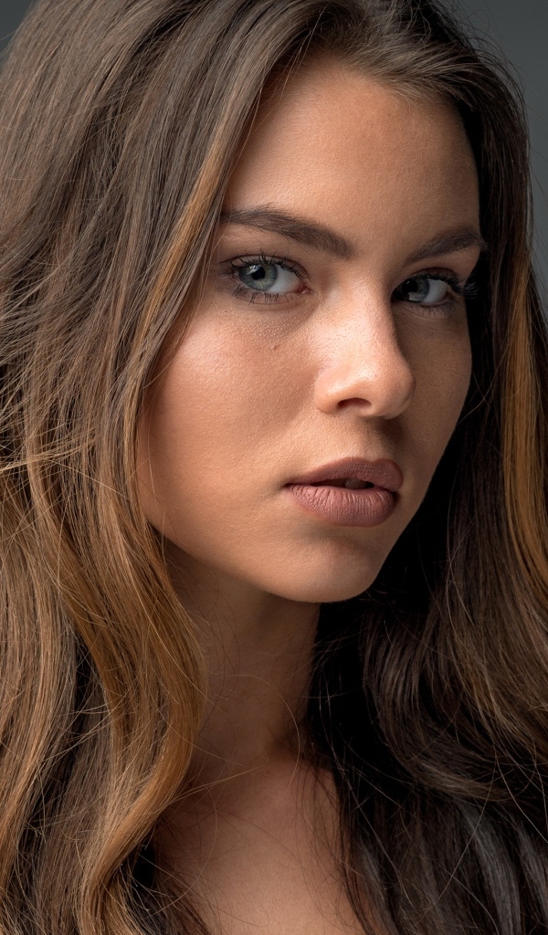 Красивая девушка шатенка на сером фоне 