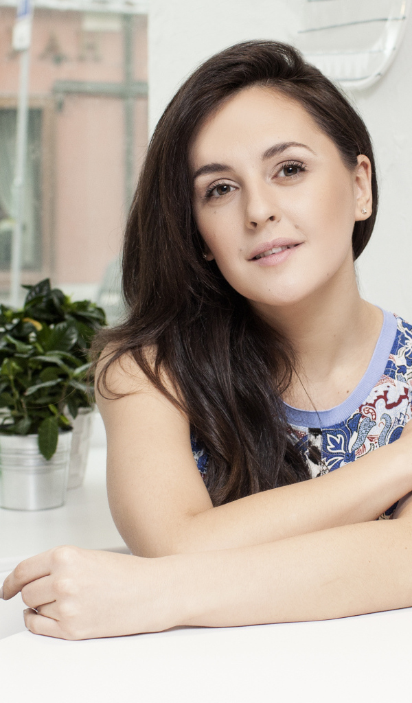 Красивая девушка брюнетка сидит за столиком в кафе 