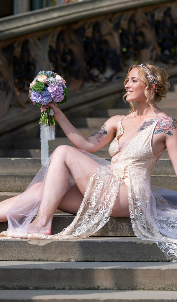 Красивая девушка невеста в платье с букетом на ступеньках