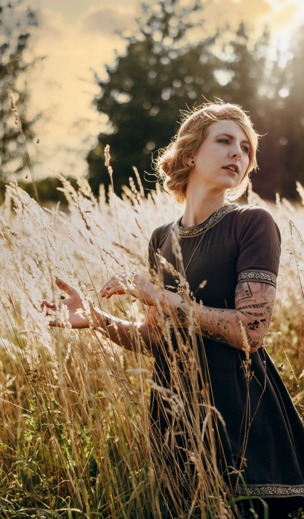 Красивая девушка в черном платье на поле с колосьями