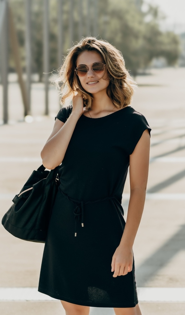 Красивая девушка в черном платье в очках