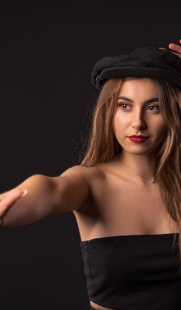 Красивая девушка в кепке на черном фоне