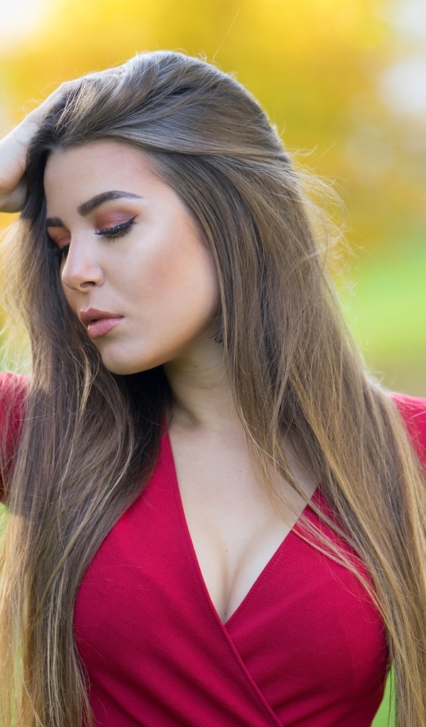 Красивая девушка в красном платье с рукой в волосах