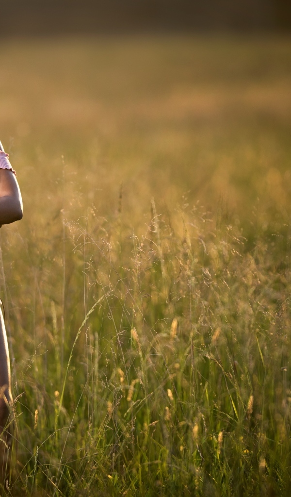 Красивая девушка стоит на поле в траве