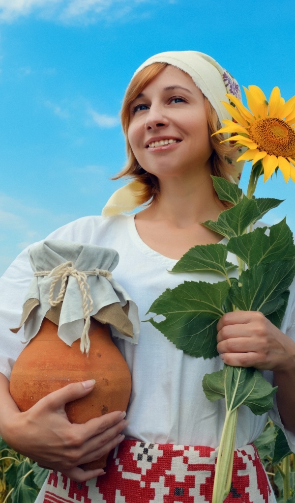 Красивая девушка с кувшином на поле с подсолнухами