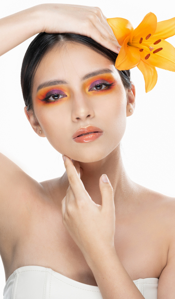 Красивая девушка с цветком лилии в волосах на белом фоне