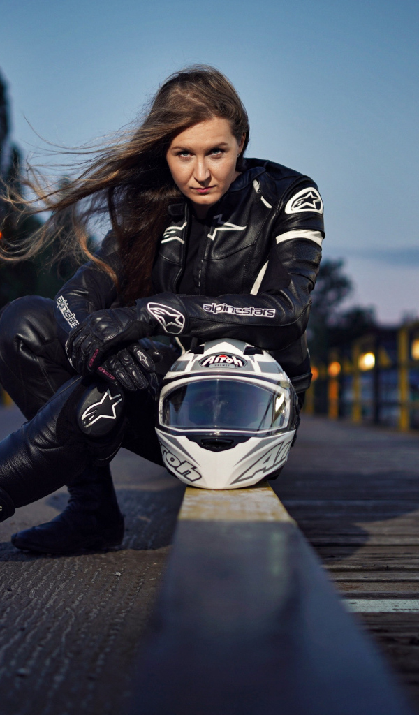 Красивая девушка с мотоциклом сидит на дороге