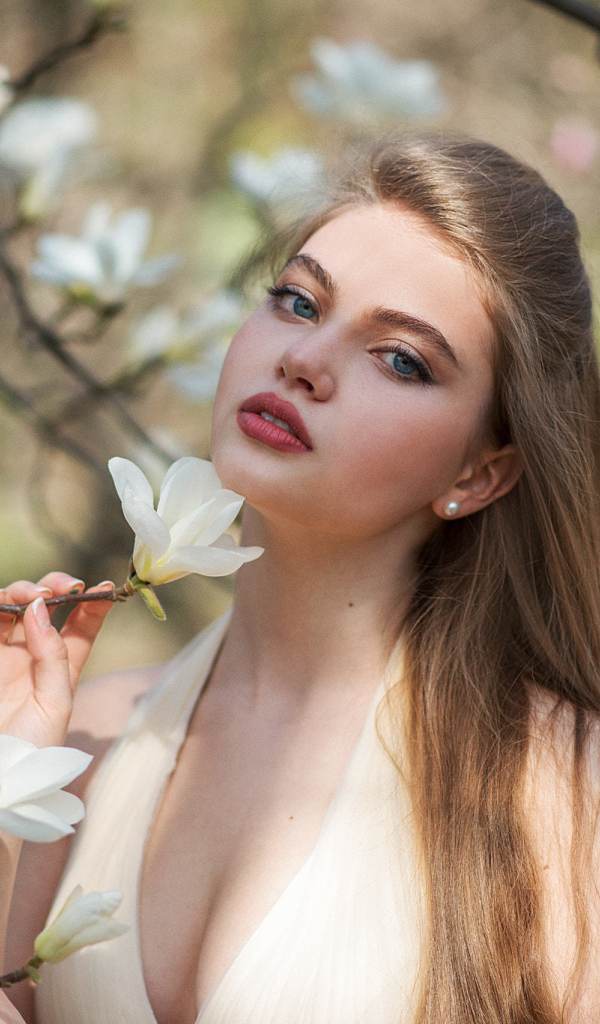 Красивая девушка с белыми цветами магнолии