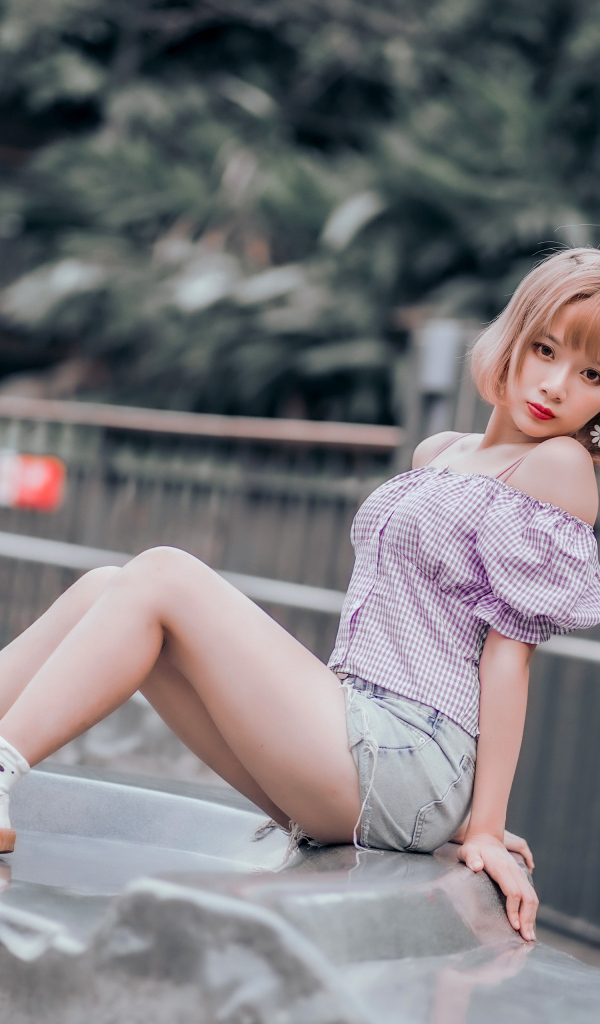 Милая девушка азиатка сидит на камне