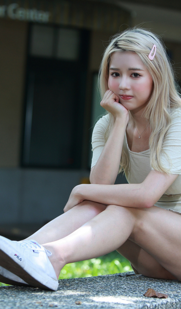 Милая азиатка сидит на холодном бетоне