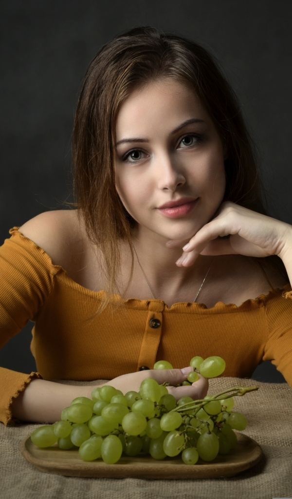 Милая шатенка ест белый виноград