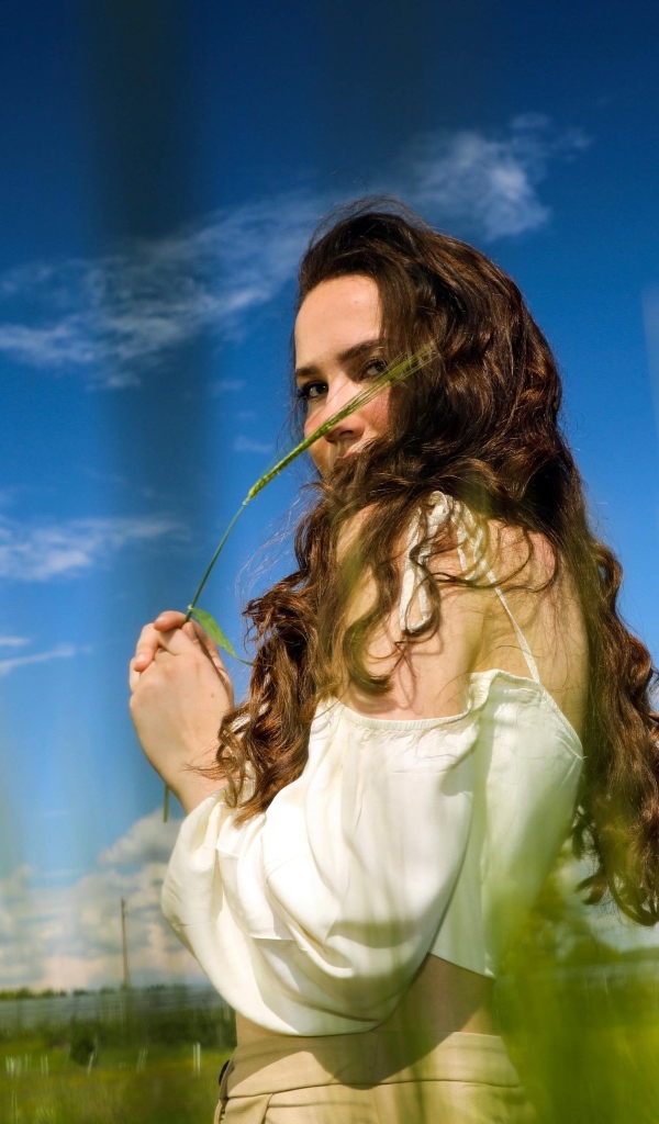 Милая девушка на поле на фоне голубого неба