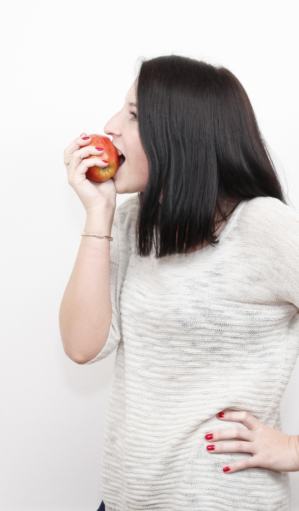 Девушка кусает красное яблоко 