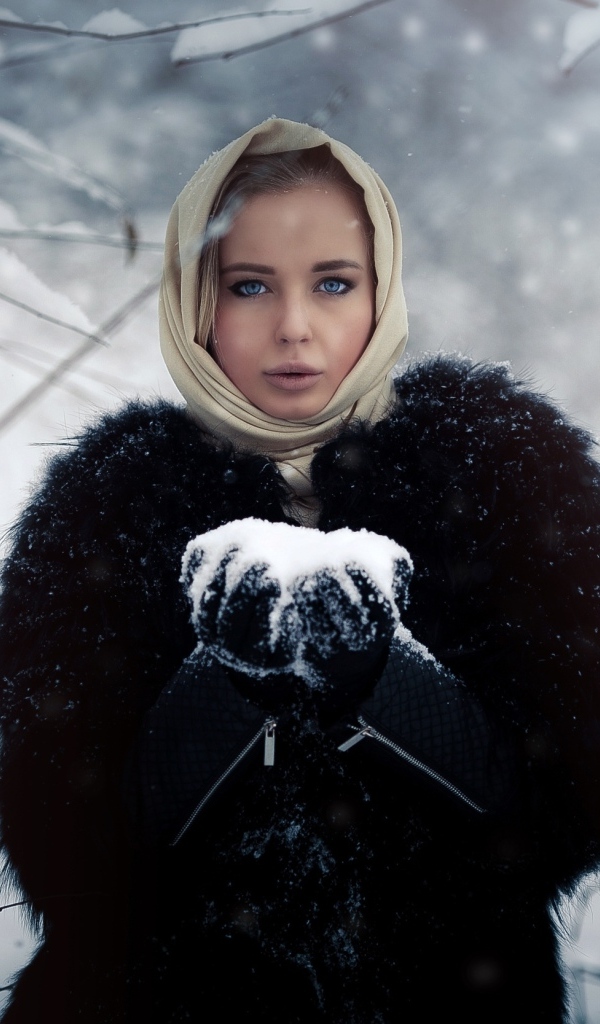 Девушка в черной шубе в заснеженном лесу