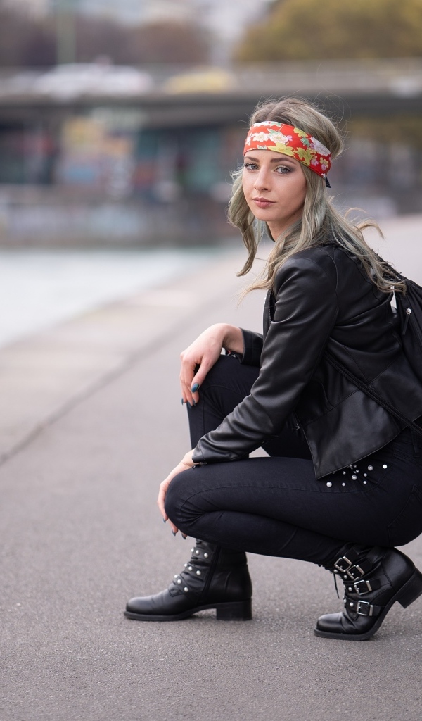 Девушка в черном костюме сидит на корточках