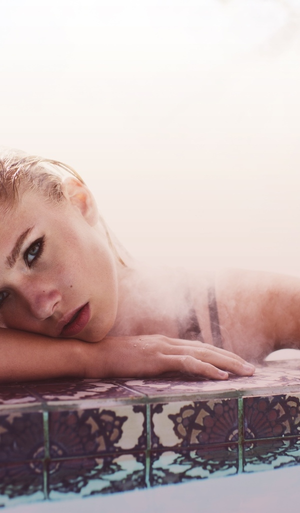 Девушка лежит в воде в бассейне