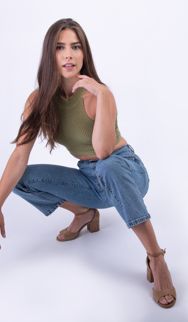 Девушка сидит на корточках на белом фоне