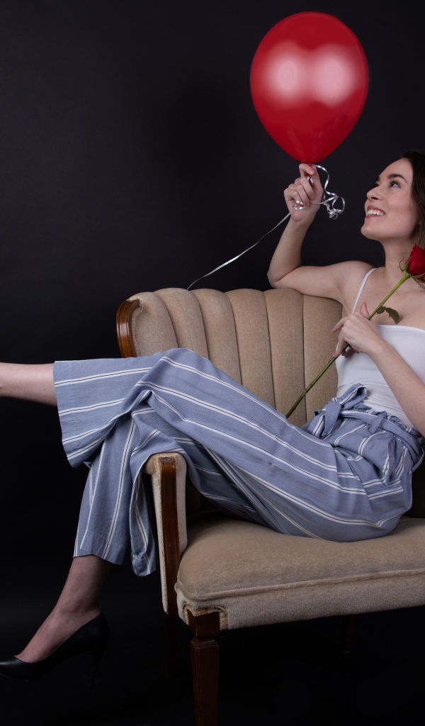 Девушка с шариком и розой сидит в кресле