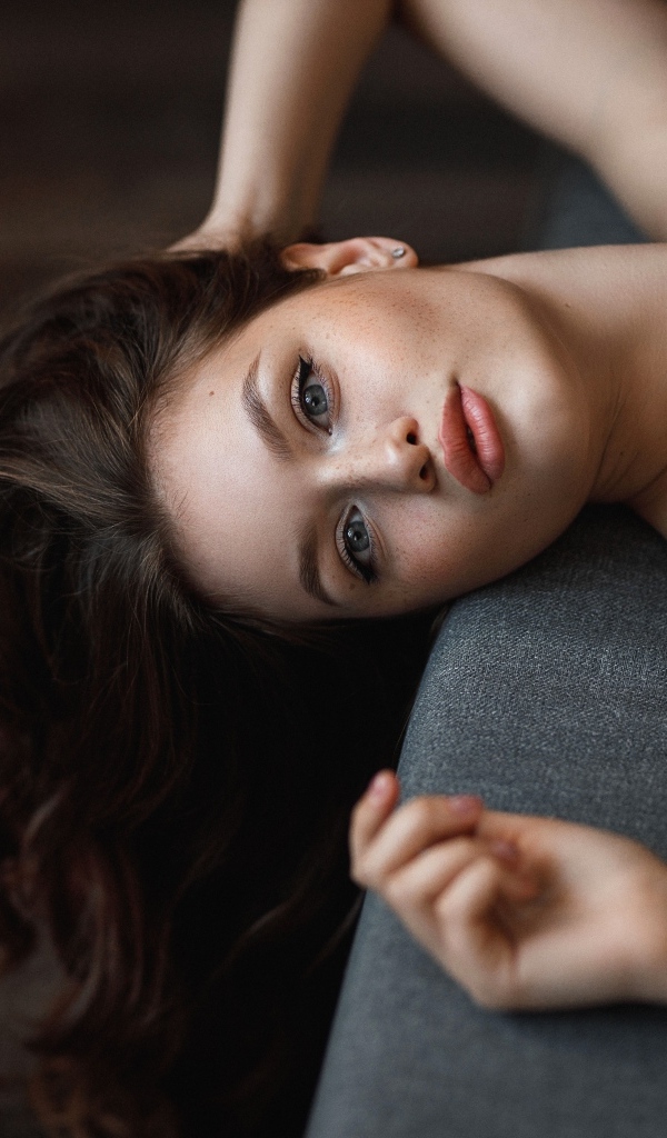 Девушка с длинными волосами лежит  на кровати