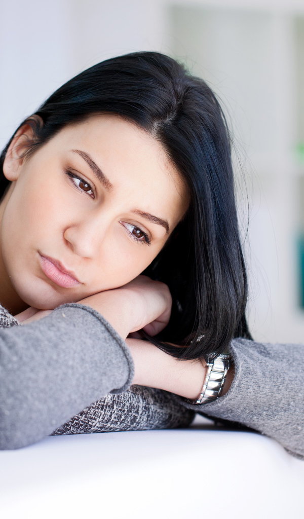 Грустная девушка брюнетка в серой кофте 