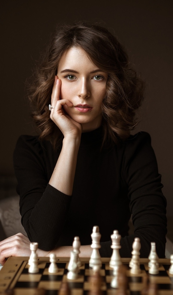 Умная молодая девушка играет в шахматы