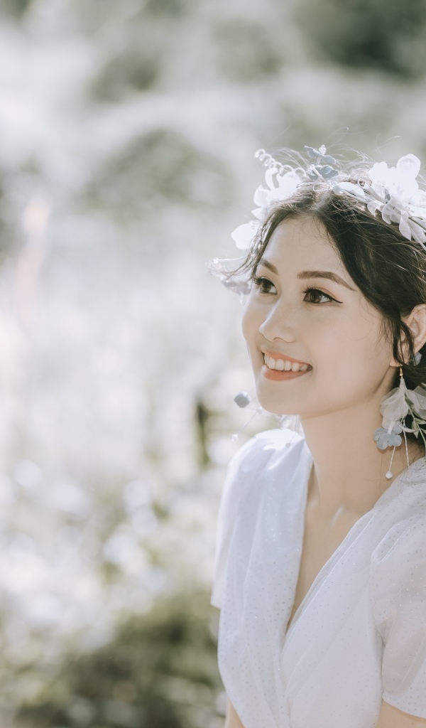 Улыбающаяся девушка азиатка в белом платье на поле