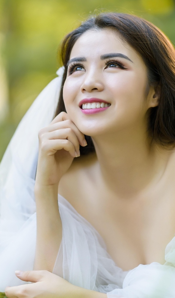 Улыбающаяся девушка азиатка в платье невесты