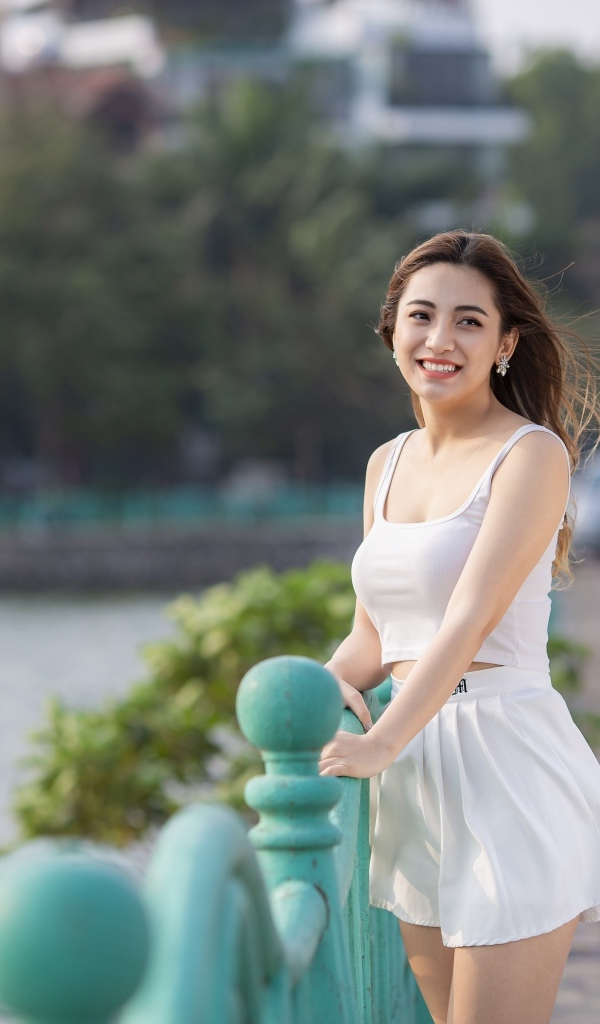 Улыбающаяся девушка азиатка в белом летнем костюме