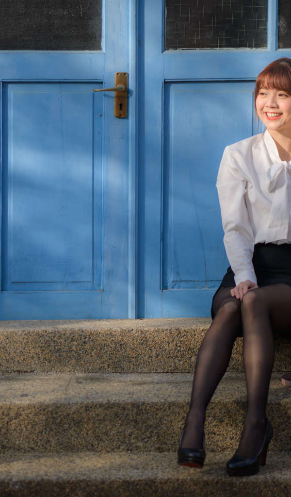 Улыбающаяся азиатка сидит на ступеньках