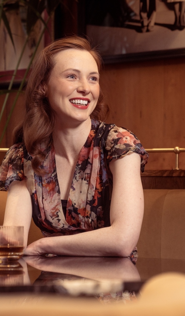 Улыбающаяся девушка за столиком в кафе