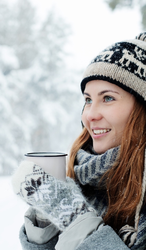 Улыбающаяся девушка с чашкой кофе зимой