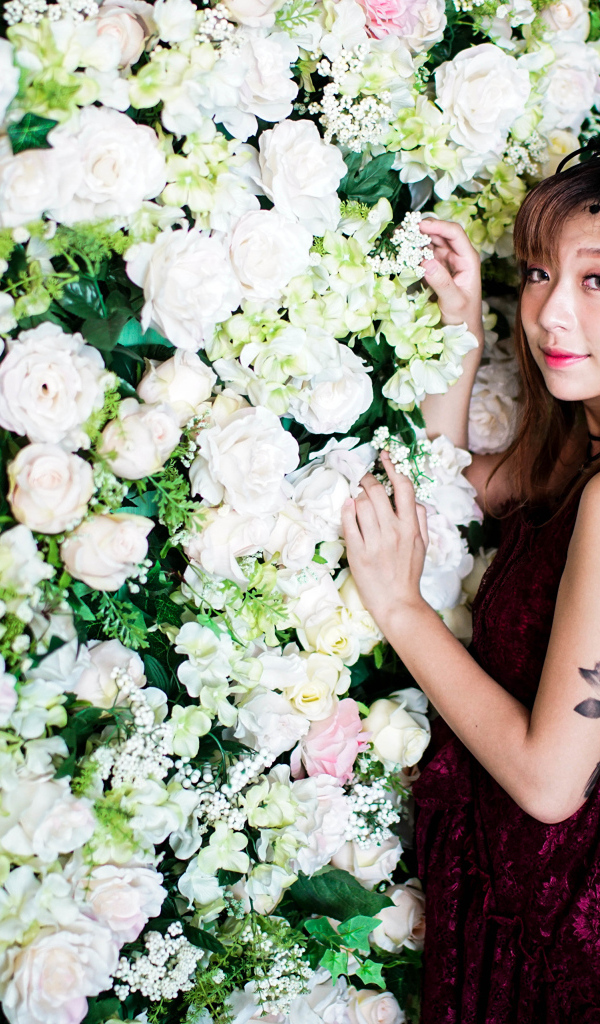 Молодая азиатка на фоне стены с розами