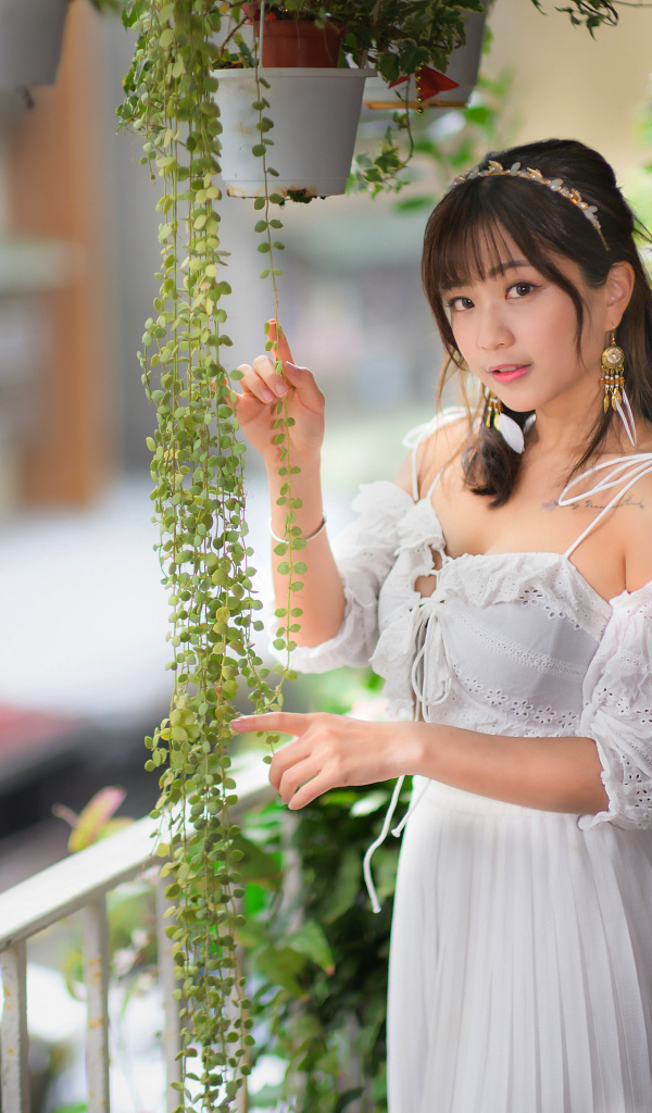 Молодая азиатка в белом платье у растений