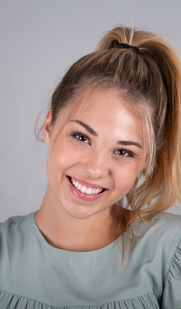 Молодая девушка блондинка на сером фоне