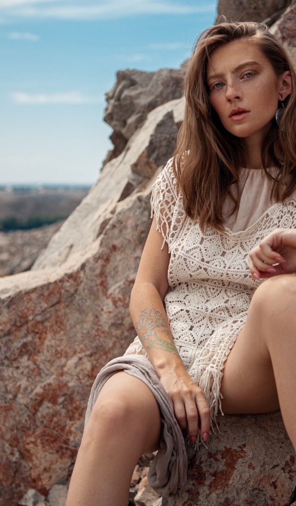 Молодая девушка сидит на камнях