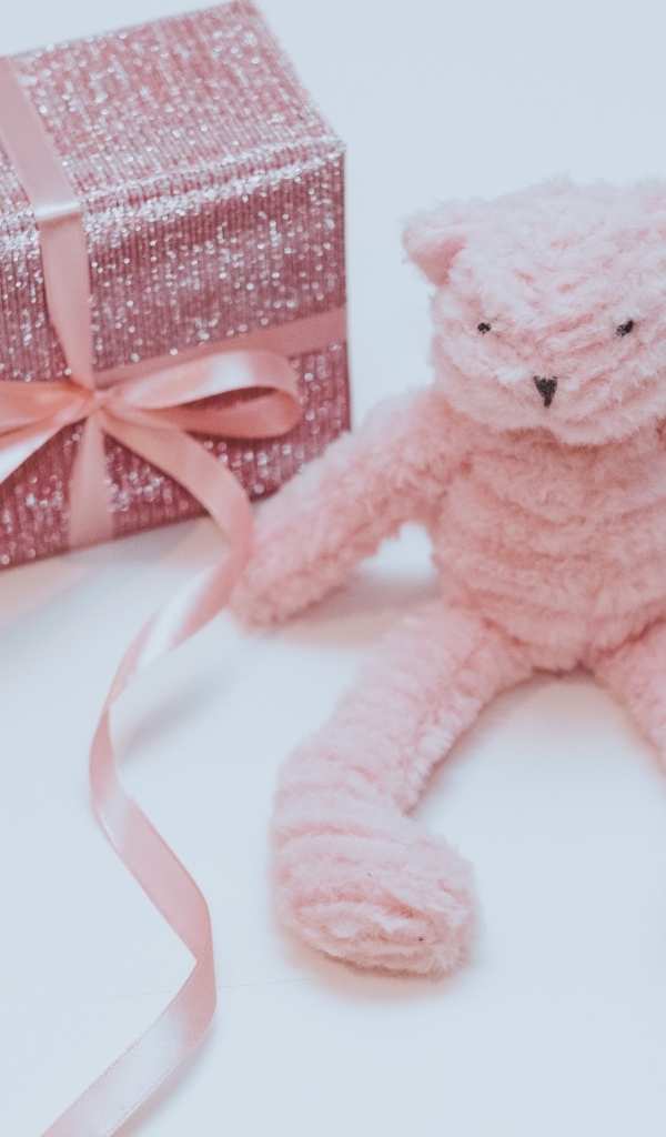 Подарок с розовой игрушкой на сером фоне