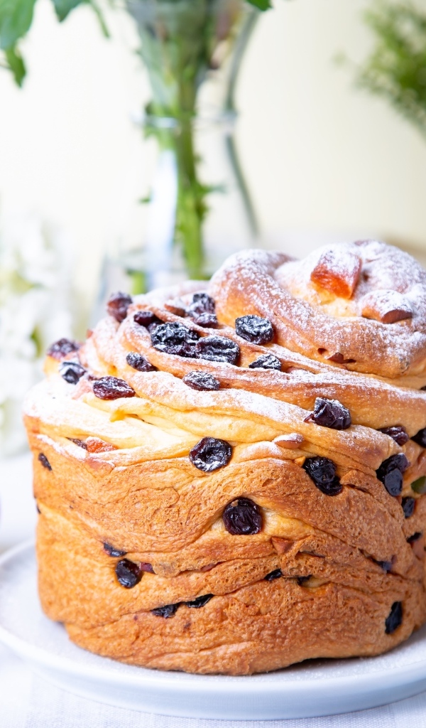 Красивый пасхальный кулич с сахарной пудрой и изюмом