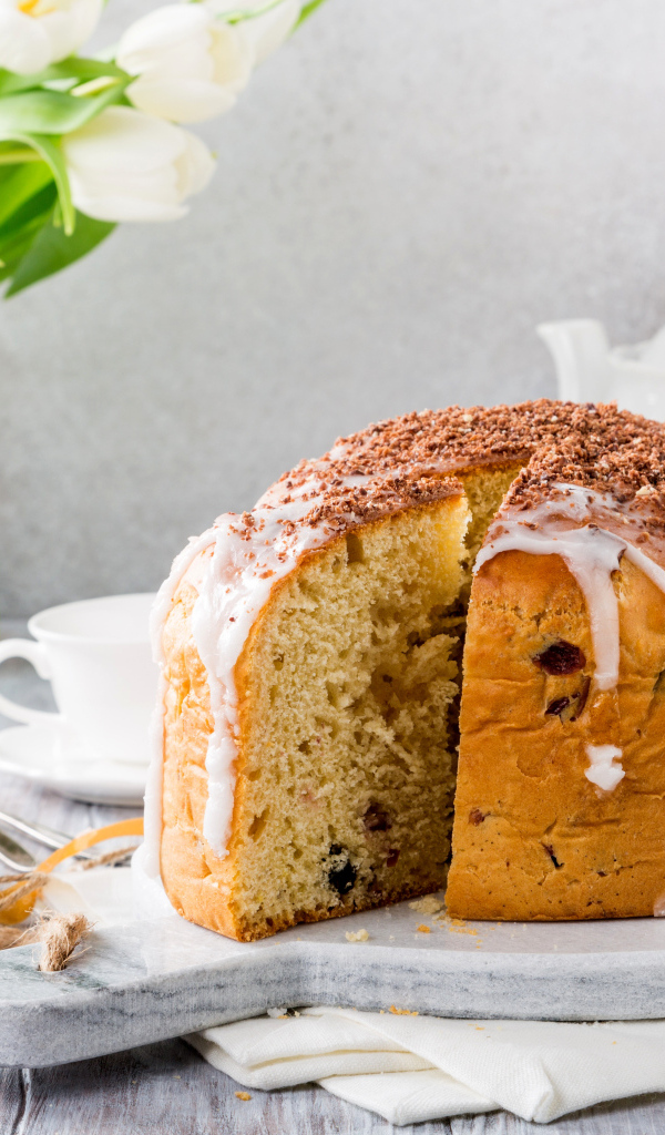 Пасхальный кулич на столе с букетом тюльпанов и сладостями