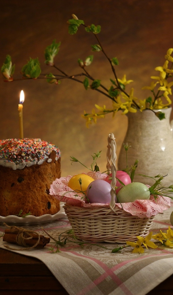 Кулич со свечой и крашеными яйцами на столе на Пасху