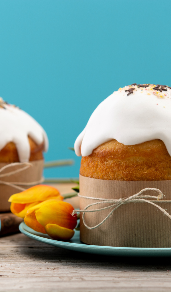 Пасхальные куличи с белой глазурью на столе с яйцами