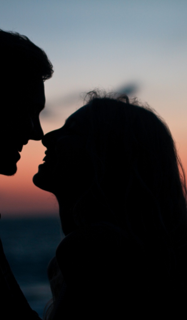 Влюбленная пара стоит на фоне заката в сумерках