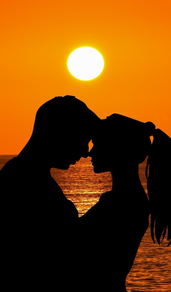 Влюбленная пара на закате солнца у моря