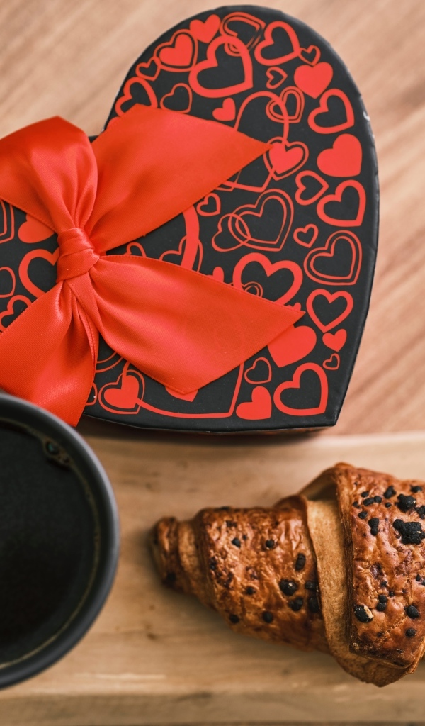 Коробка в форме сердца, кофе и круассан на столе