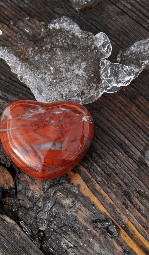 Сердце из камня на деревянной лавке с тающим снегом