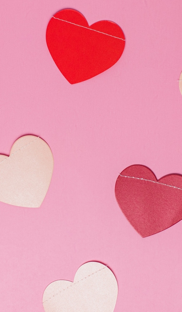 Бумажные разноцветные сердечки на розовом фоне