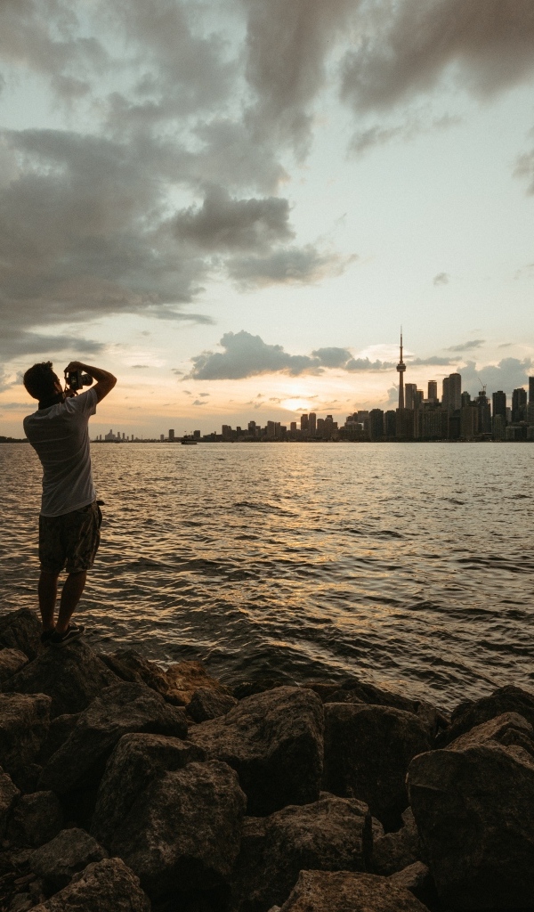 Мужчина делает фото города у моря