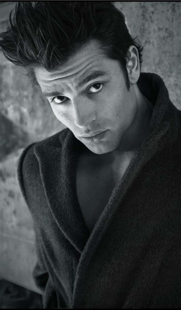 Красивый мужчина в черном пальто у стены