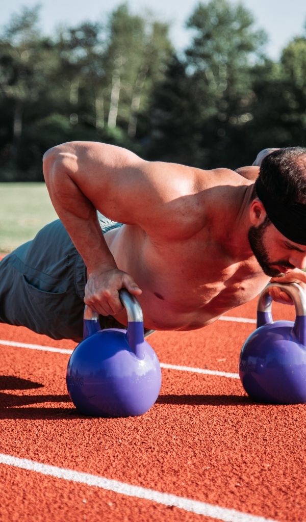 Мужчина спортсмен занимается с гирями