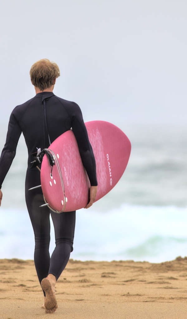 Мужчина серфингист идет к морю